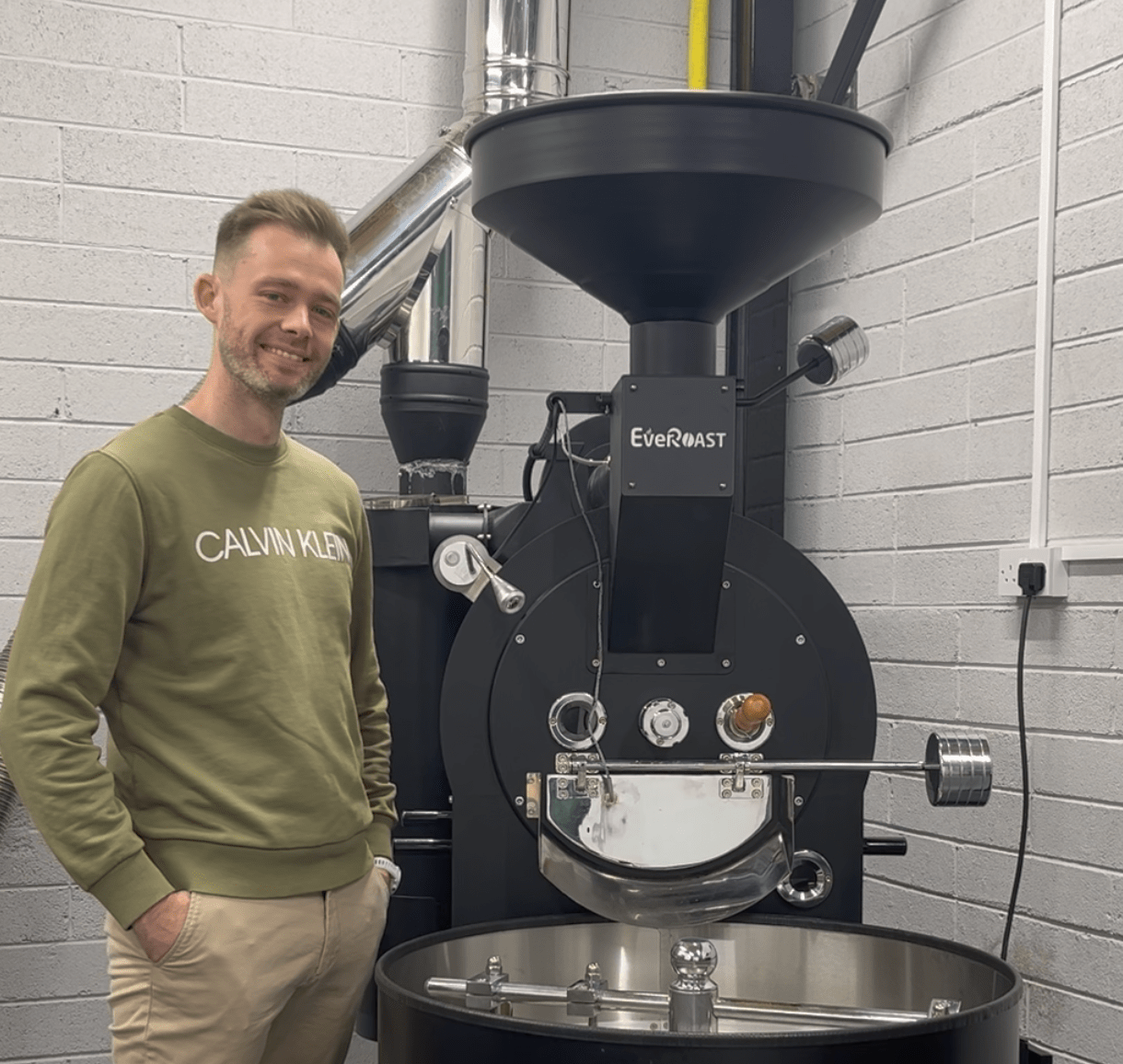 Darren Kelly the founder of Behind the Label roastery, standing infront of his roaster.